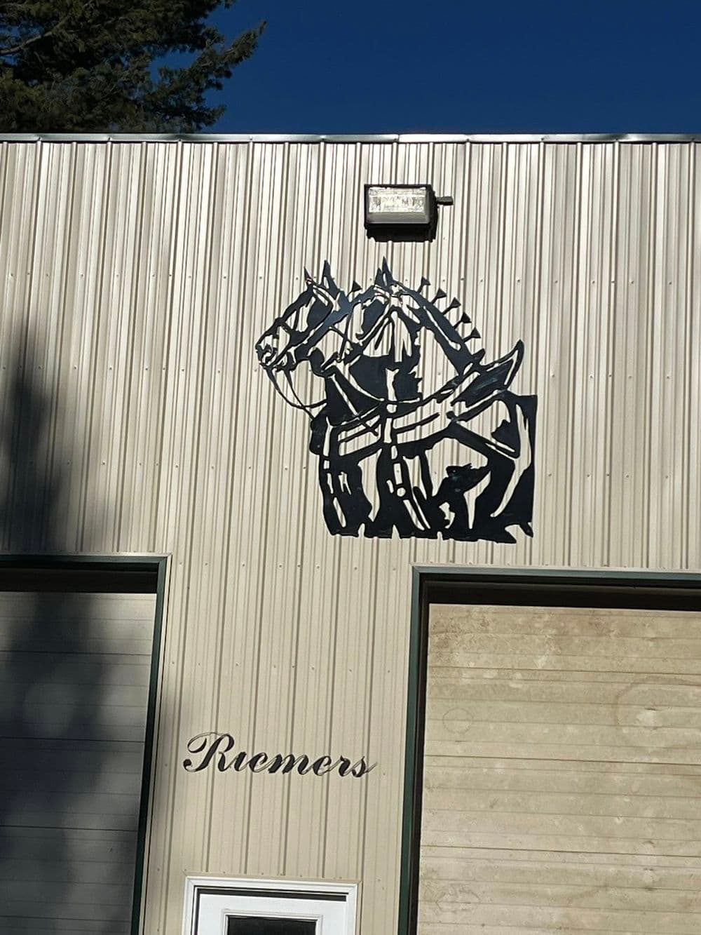 Horseshoe and knight silhouette sign on a metal building facade. Riemers branding displayed.