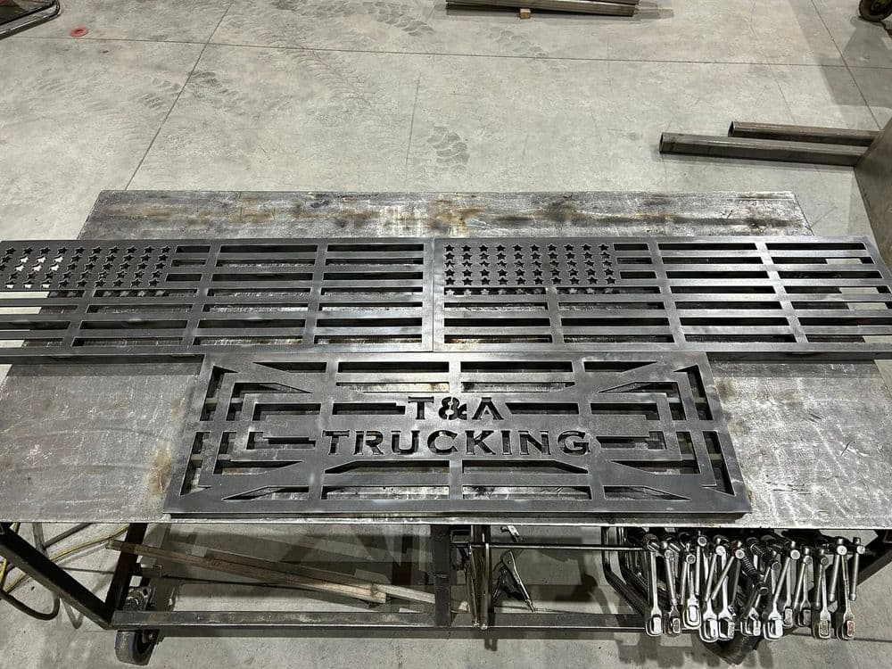 Metal sign for T&A Trucking, featuring a design with star patterns and industrial tools nearby.