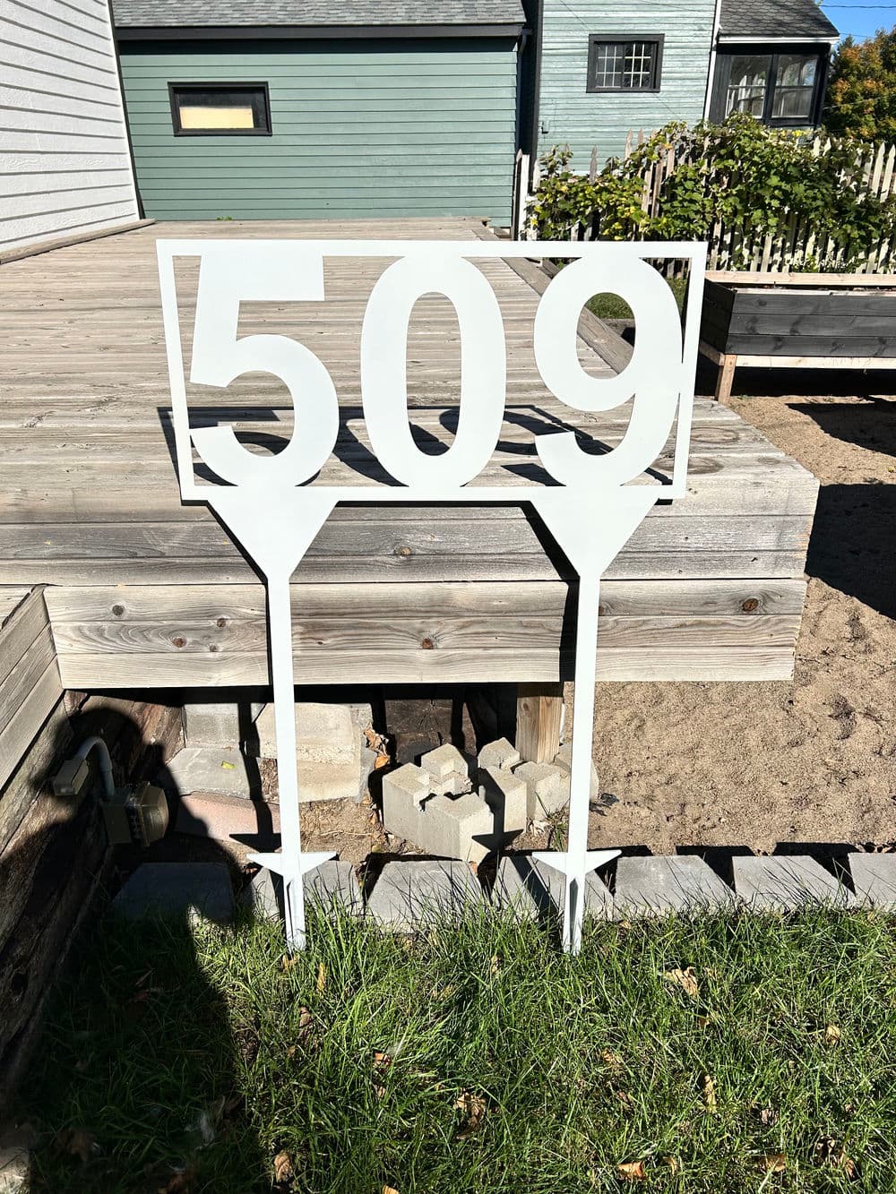White sign displaying the number 509 on a wooden deck in a residential area.