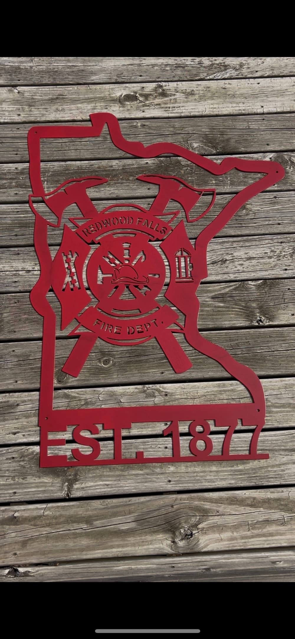 Redwood Falls Fire Department emblem in Minnesota, established 1877, on wooden background.