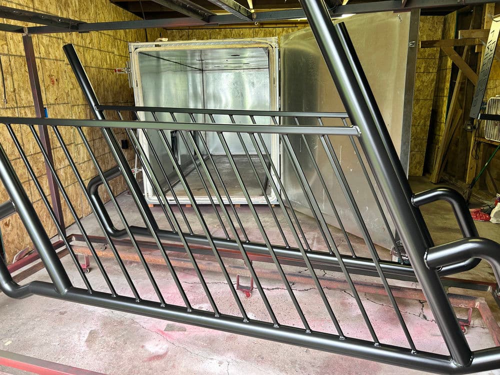 Metal bike rack under construction in a workshop with tools and materials visible.