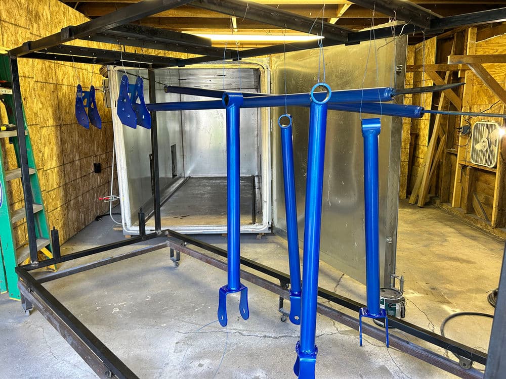 Blue-painted metal components hanging in a workshop, ready for assembly or finishing.