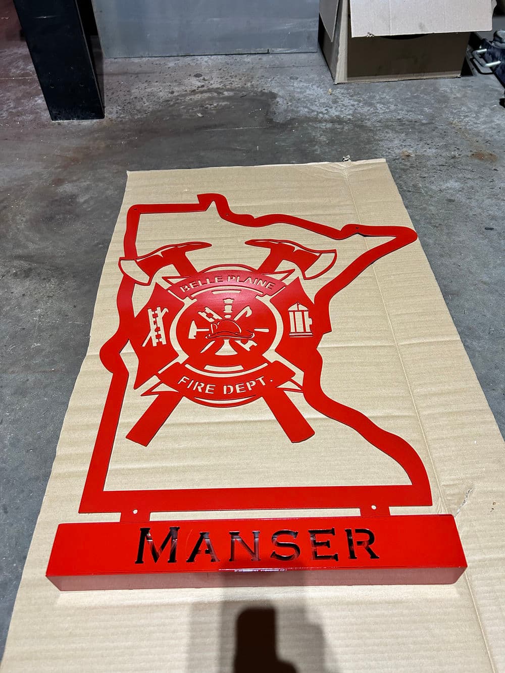 Red Minnesota fire department metal plaque featuring "Hell's Blain Fire Dept" and "Manser" name.